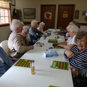 A Group Of Women Gathered Around A Table For Bingo