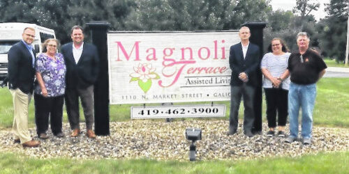 A Group Of People Standing In Front Of Magnolia Terrace Sign